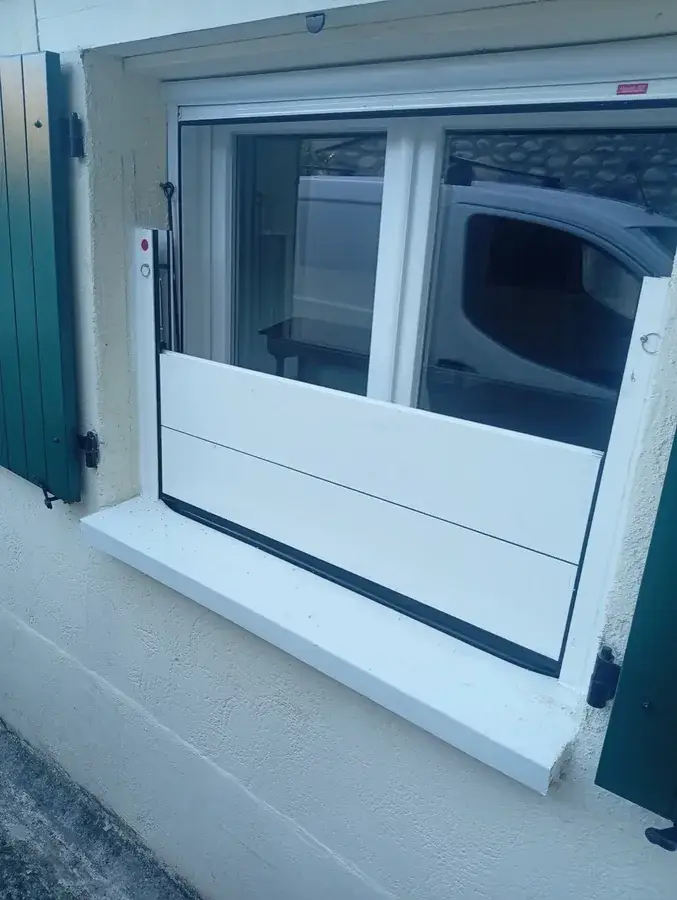 Barrera apilable protegiendo una ventana baja de una vivienda